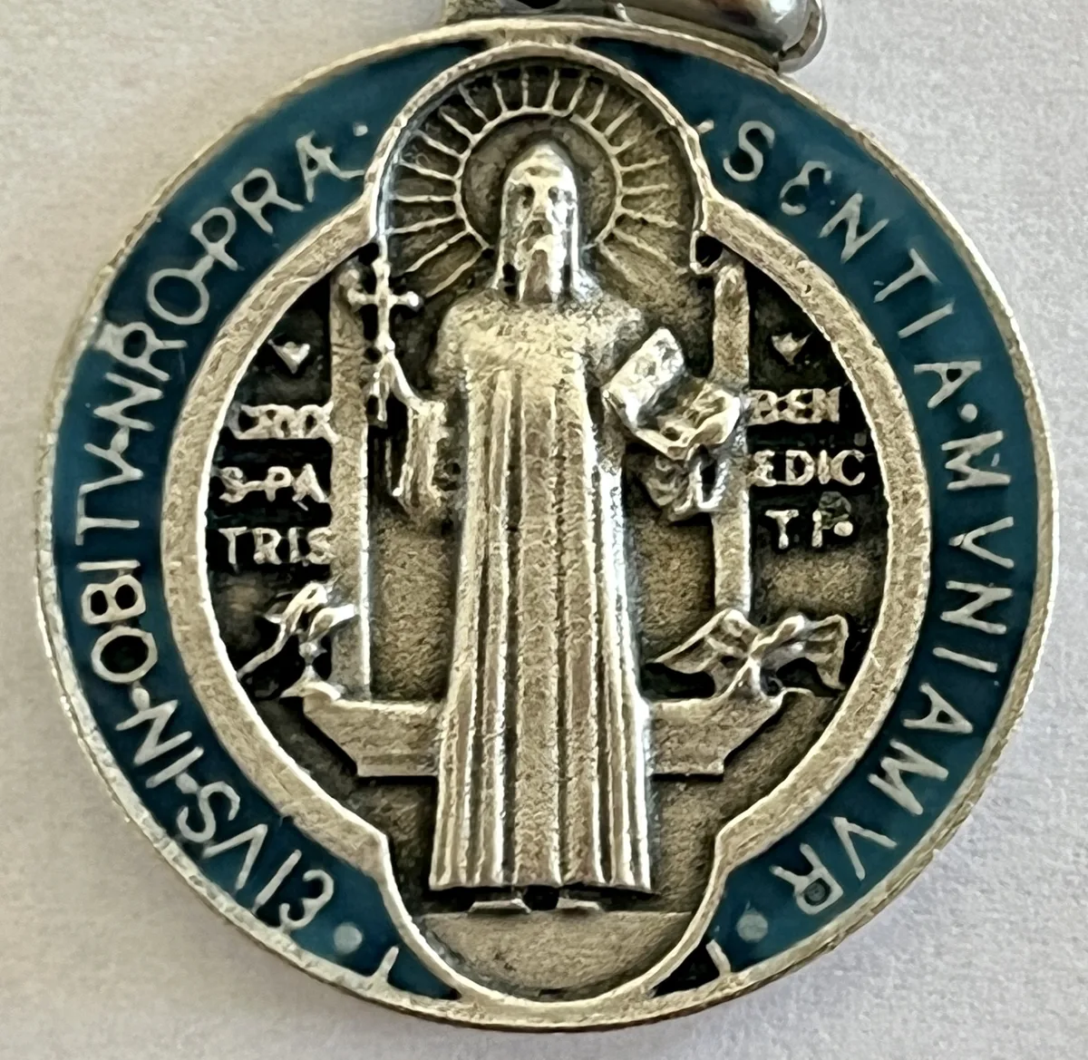 The front of the Saint Benedict Medal, Saint Benedict holding the cross and the Rule, with the cup and the raven