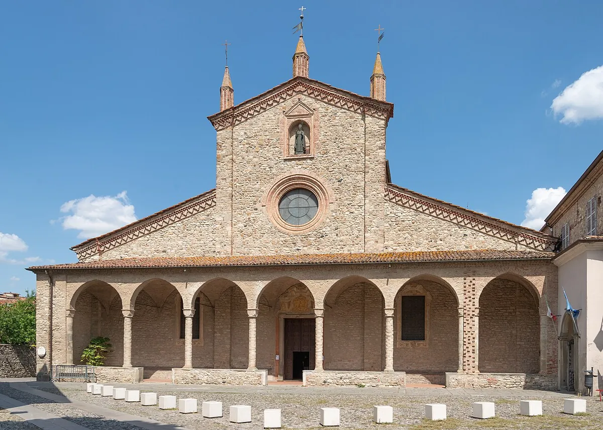 The abbey of San Colombano at Bobbio seen across the town, a long stone church with a square campanile against wooded hills