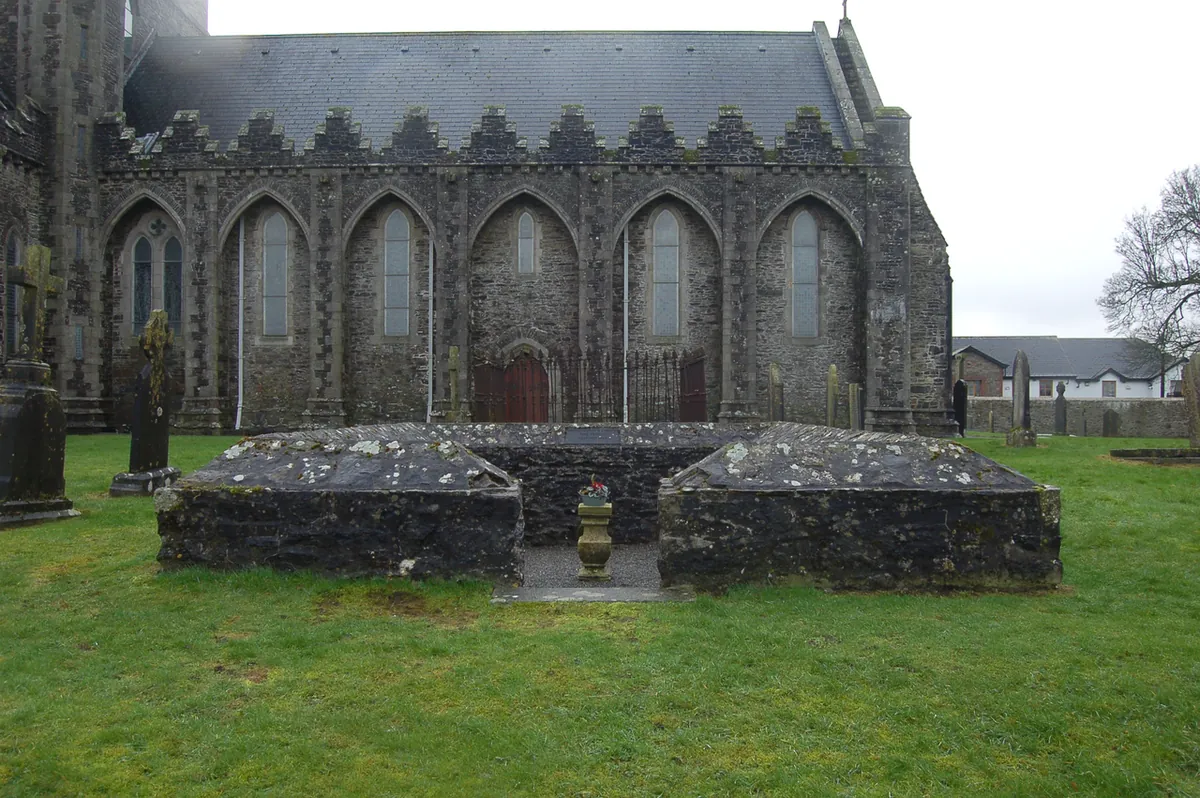 The low stone foundations of the fire temple in the grounds of Saint Brigid's Cathedral at Kildare, with the cathedral behind
