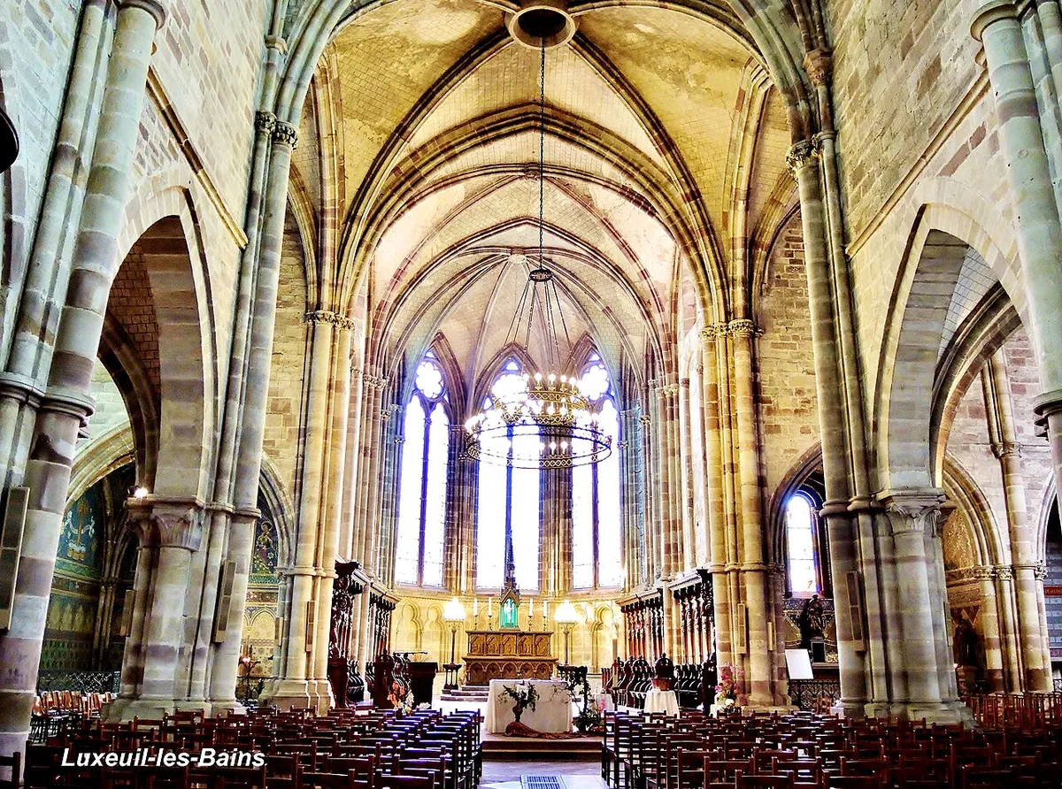 The Gothic nave of the abbey church at Luxeuil-les-Bains, tall pale stone piers rising to a vaulted roof