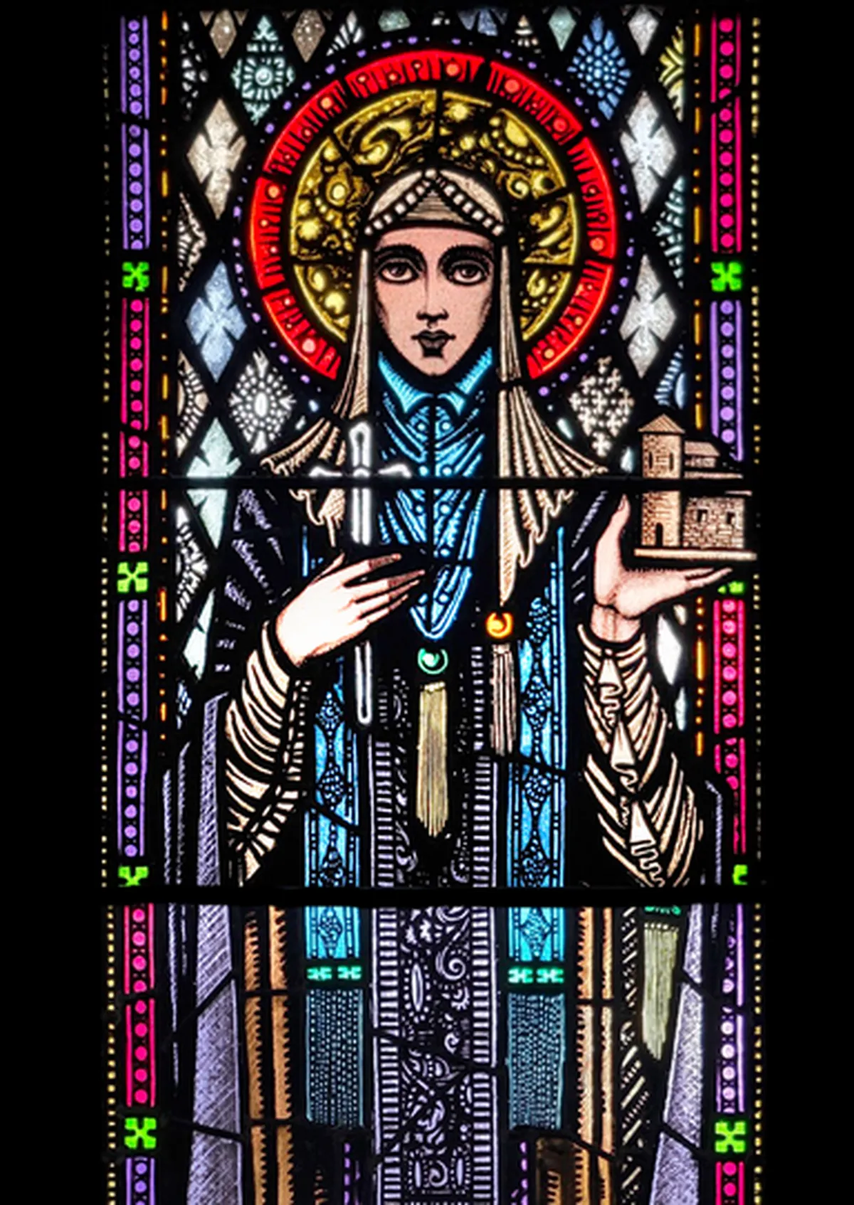 Harry Clarke's Saint Brigid in stained glass, the abbess with a gold halo holding a crozier in one hand and a small model church in the other