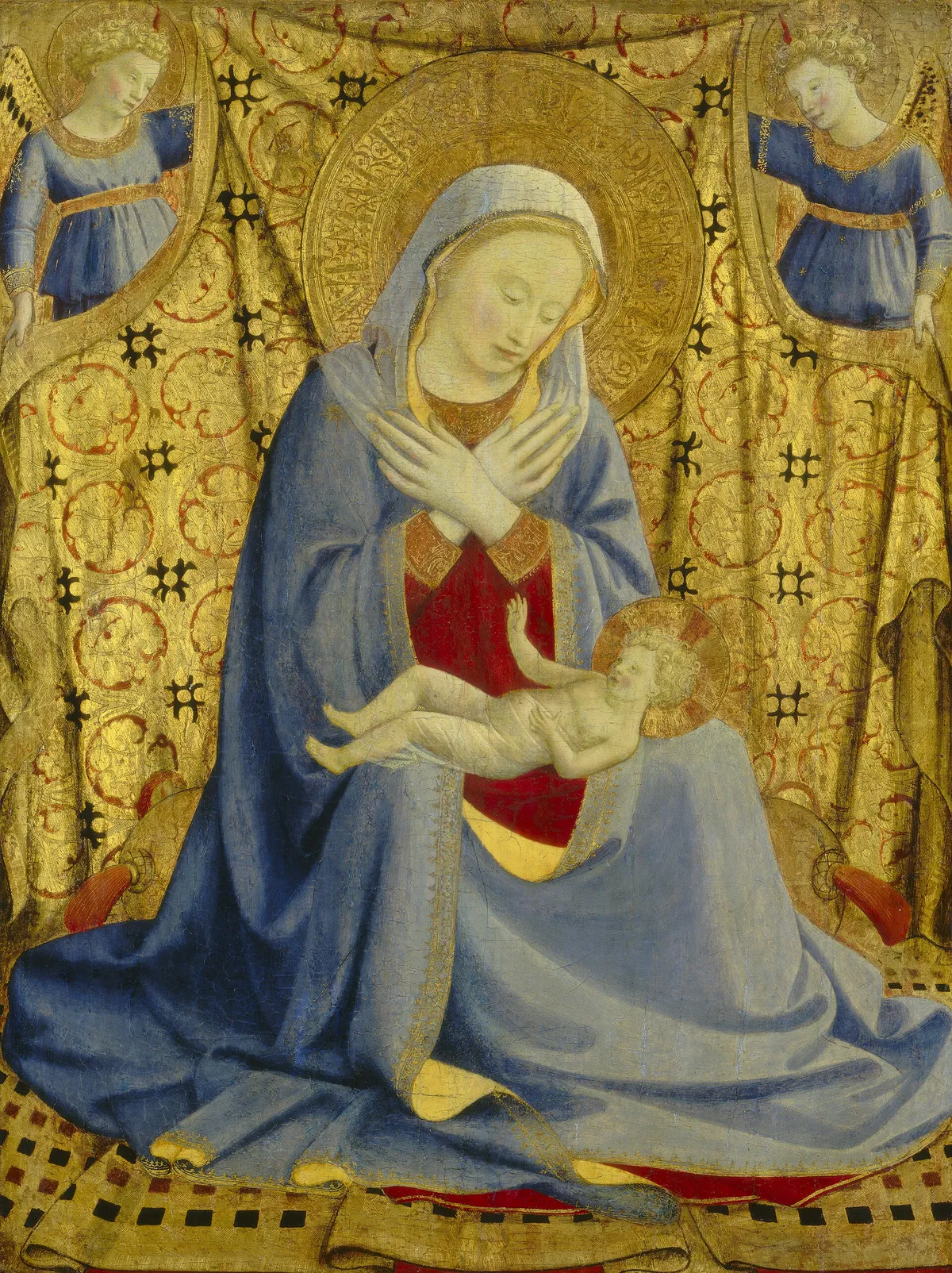 Fra Angelico's Madonna of Humility: the Virgin seated on a cushion, arms crossed over her breast, the Child on her lap, two angels holding a gold cloth